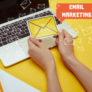 cropped image of woman holding envelope sign near laptop with"email marketing" lettering and email